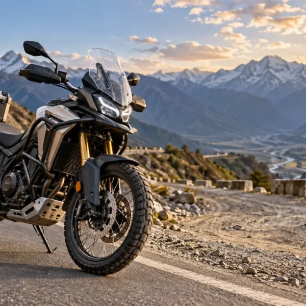 Modern adventure motorcycle riding on an Indian mountain road with paved and gravel terrain.